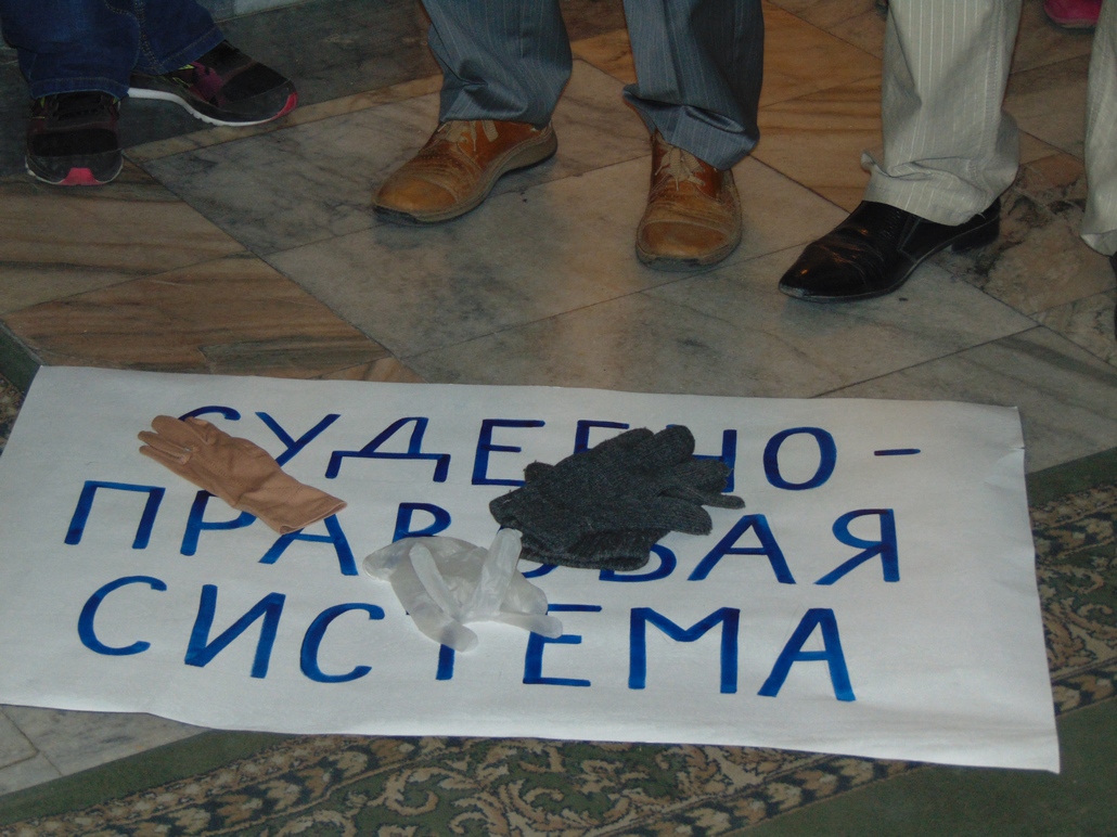 Участники пикета бросили символические перчатки на плакат с надписью "судебно-правовая система" 