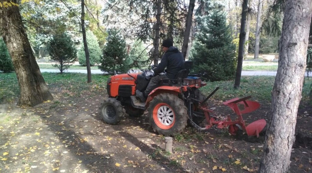 Трактор осторожно пашет между деревьями в алматинском парке; фото: Ц-1