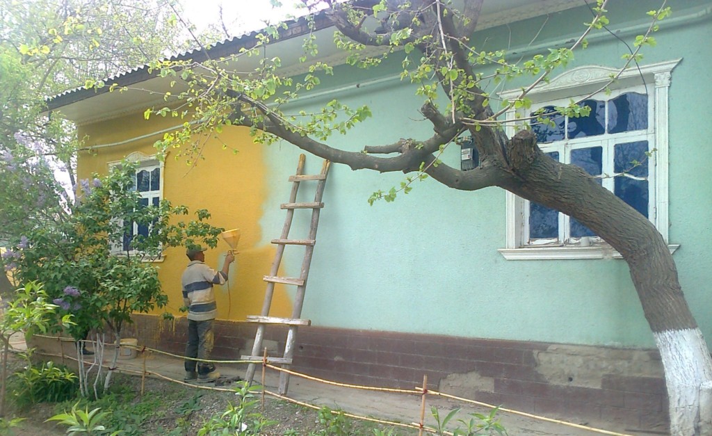 Исраил Ризаев перекрашивает свой дом в желтый цвет в Сырдарье; фото: "Эзгулик"